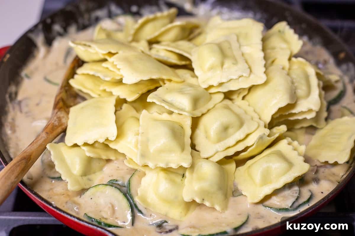 Baked Ravioli Alfredo Casserole with Creamy Parmesan Sauce 9 Uncooked ravioli is added to the skillet.