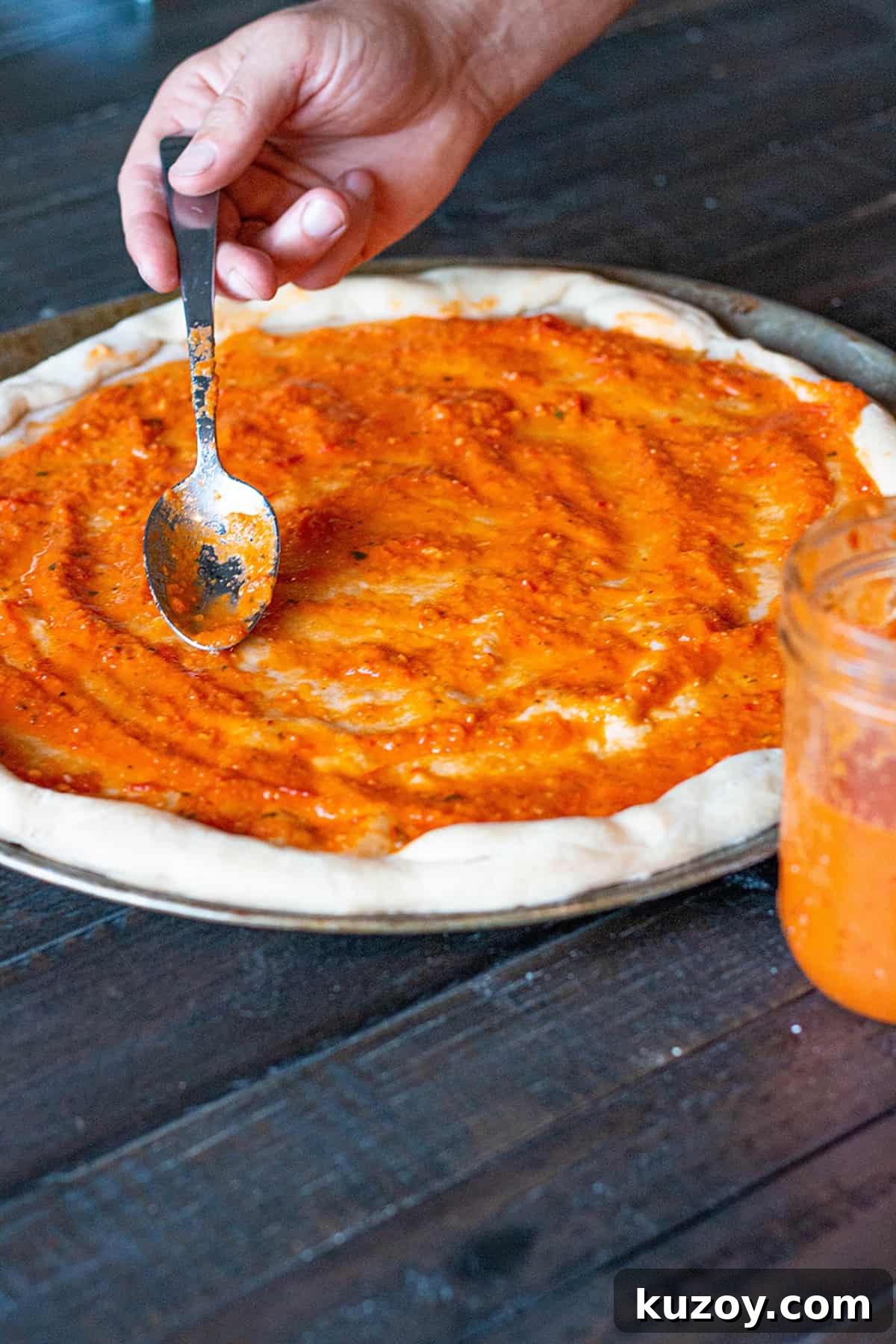 Garden Tomato Pizza Sauce Recipe for Homemade Pies 2 Fresh homemade pizza dough with homemade pizza sauce being spread on it.