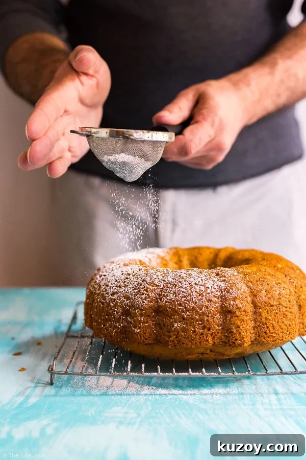Classic Grandma’s Banana Cake Recipe for Moist, Flavorful Slices 7 A man using a sieve to sprinkle powdered sugar onto a Poppy Seed Cake.