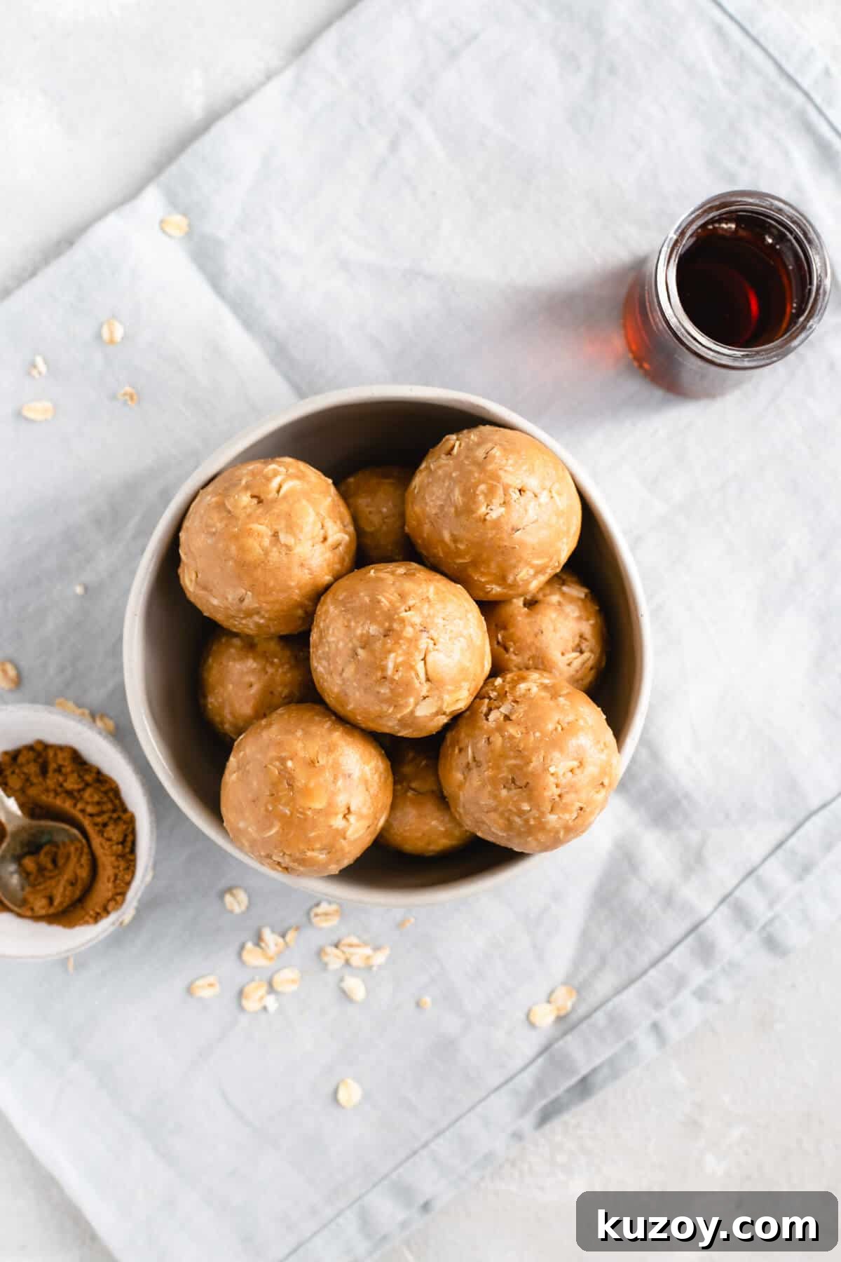 Coconut Peanut Butter Energy Bites with Warm Spices 6 Overhead shot of bowl filled with coconut and peanut butter spiced energy bites with maple syrup and mixed spice on side