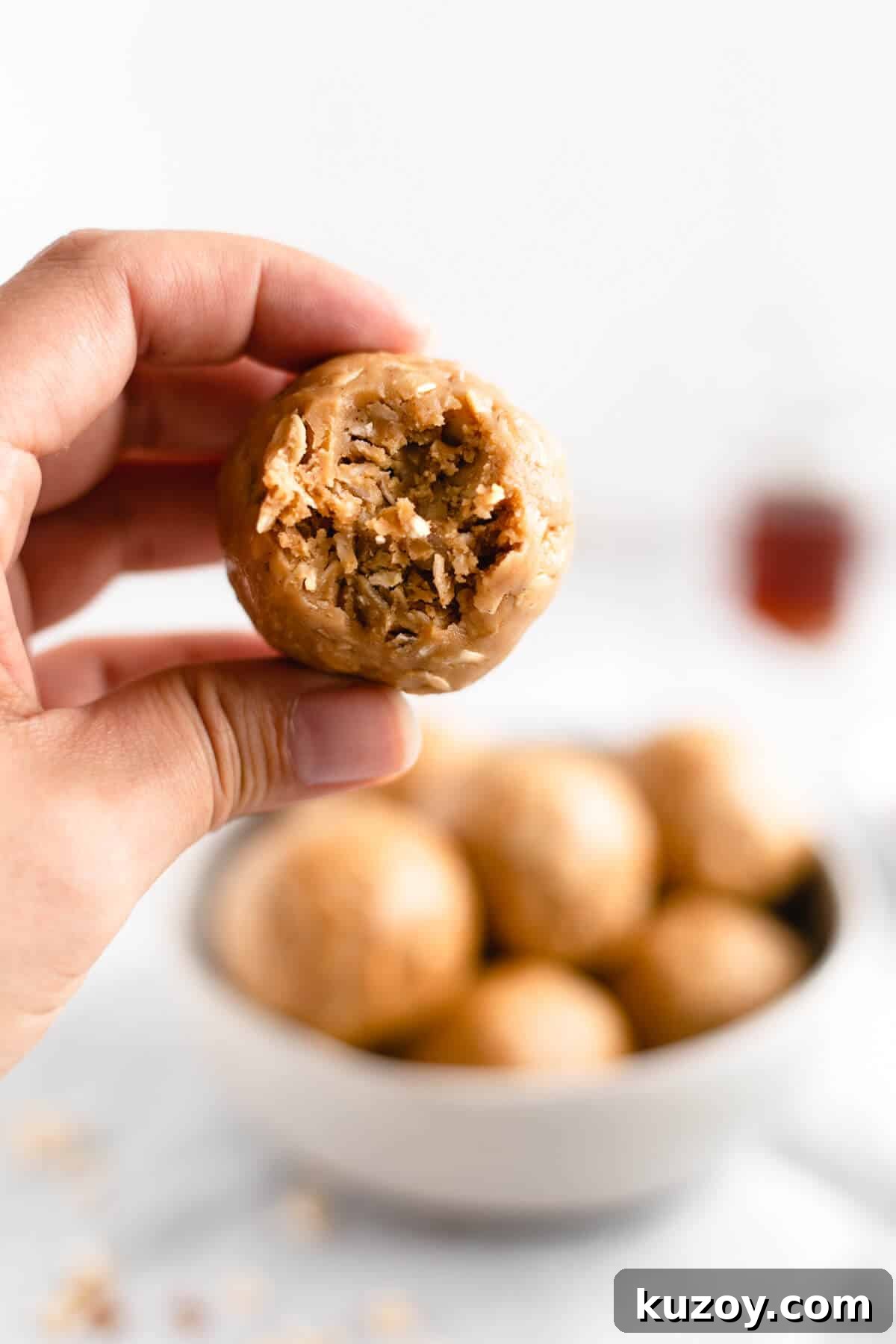 Coconut Peanut Butter Energy Bites with Warm Spices 8 A close-up of coconut and peanut butter spiced energy bite being held in someone's hand