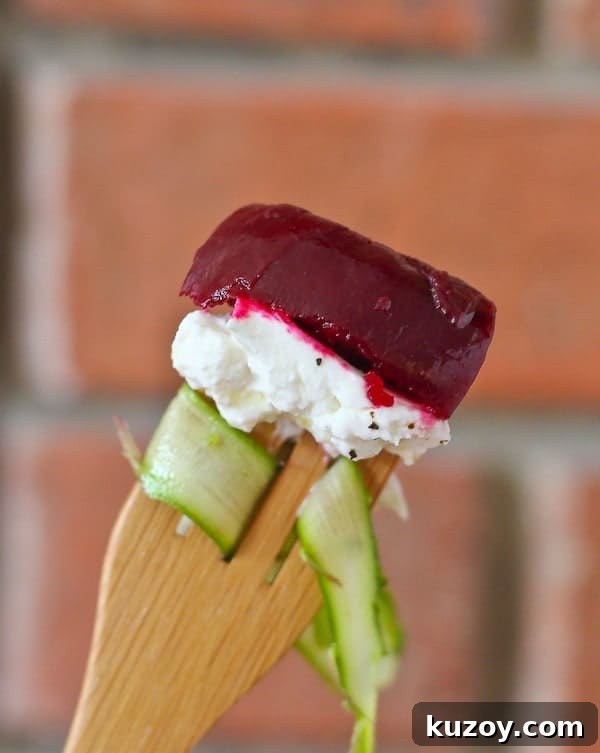 Asparagus Ribbon Salad with Beets and Creamy Burrata 5 Closeup of an asparagus ribbon, chunk of burrata, and sliced beet on a wooden fork.