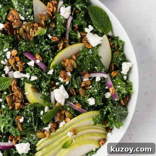 Asparagus Ribbon Salad with Beets and Creamy Burrata 8 Image of a kale salad in a white bowl topped with pears, feta cheese, red onions, and savory granola.