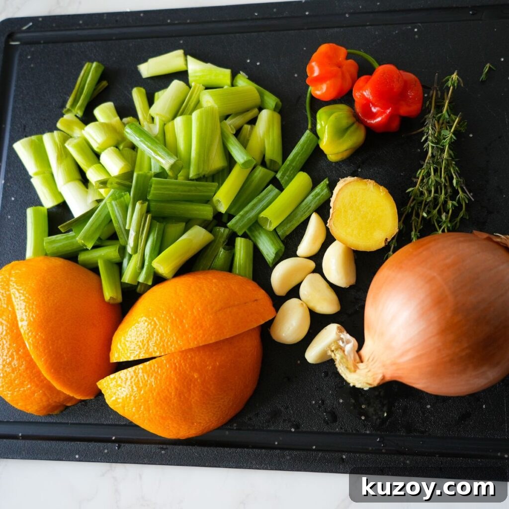 Authentic Jamaican Jerk Marinade Recipe for Chicken & Pork 3 Chopped oranges, garlic, scallions, thyme, ginger and scotch bonnet peppers on a cutting board.