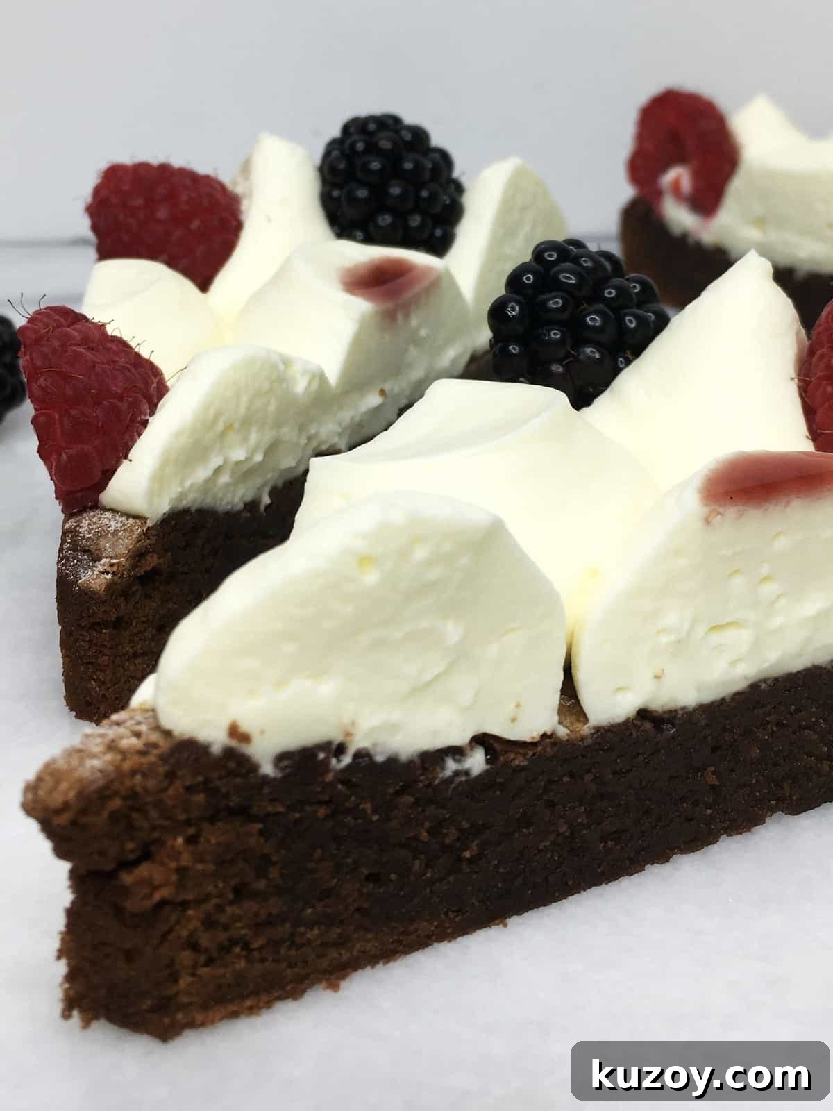 Decadent Brownie Birthday Cake Recipe 3 A couple of brownies decorated with cream and fresh fruits on a marble board