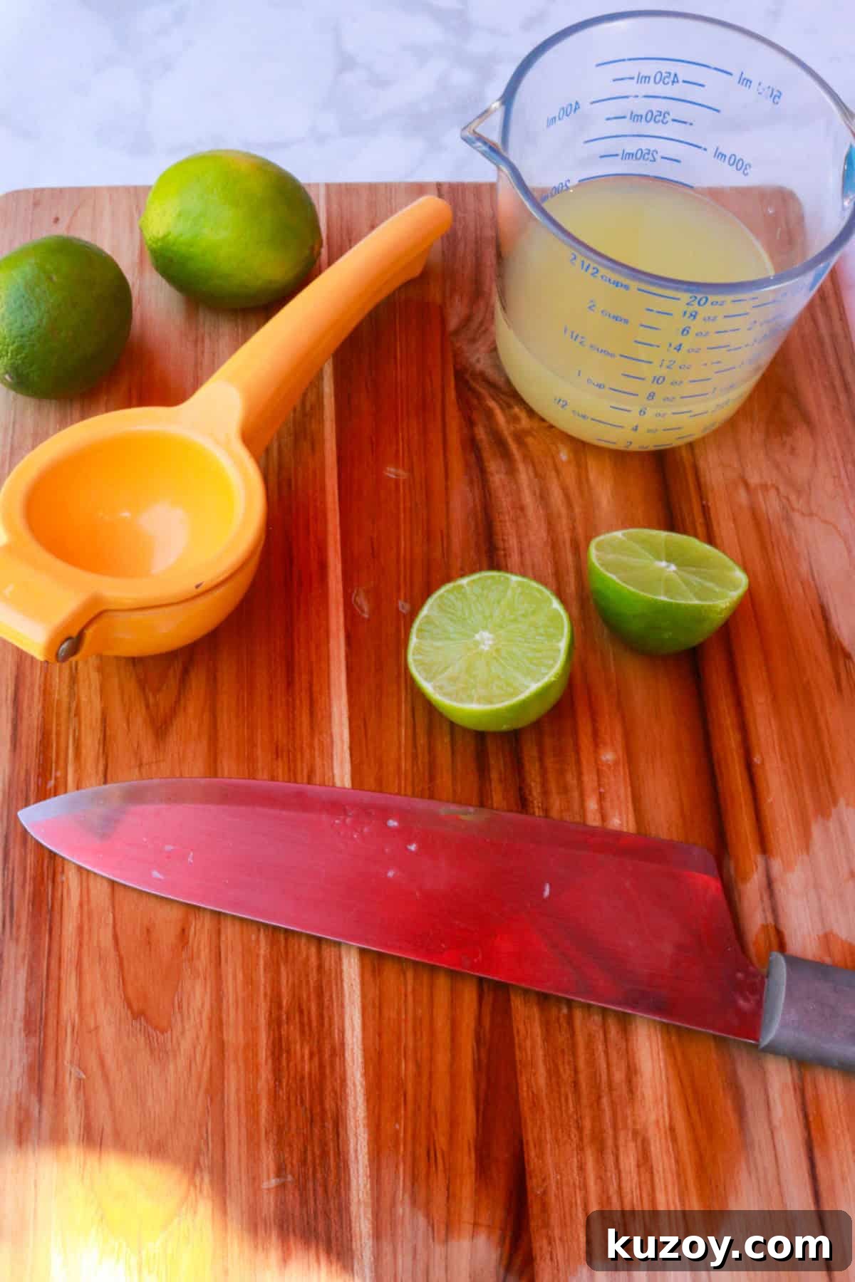Refreshing Strawberry Limeade Recipe: Homemade Strawberry-Lime Cooler 7 a cutting board with a knife, cut lemons, a measuring cup with lime juice and a citrus squeezer