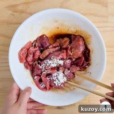 Mixing beef slices with beef marinading ingredients in a bowl with chopsticks