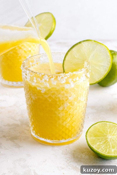 Frozen Pineapple Margarita Recipe — 4-Ingredient Tropical Cocktail 2 pineapple margarita being poured into glass