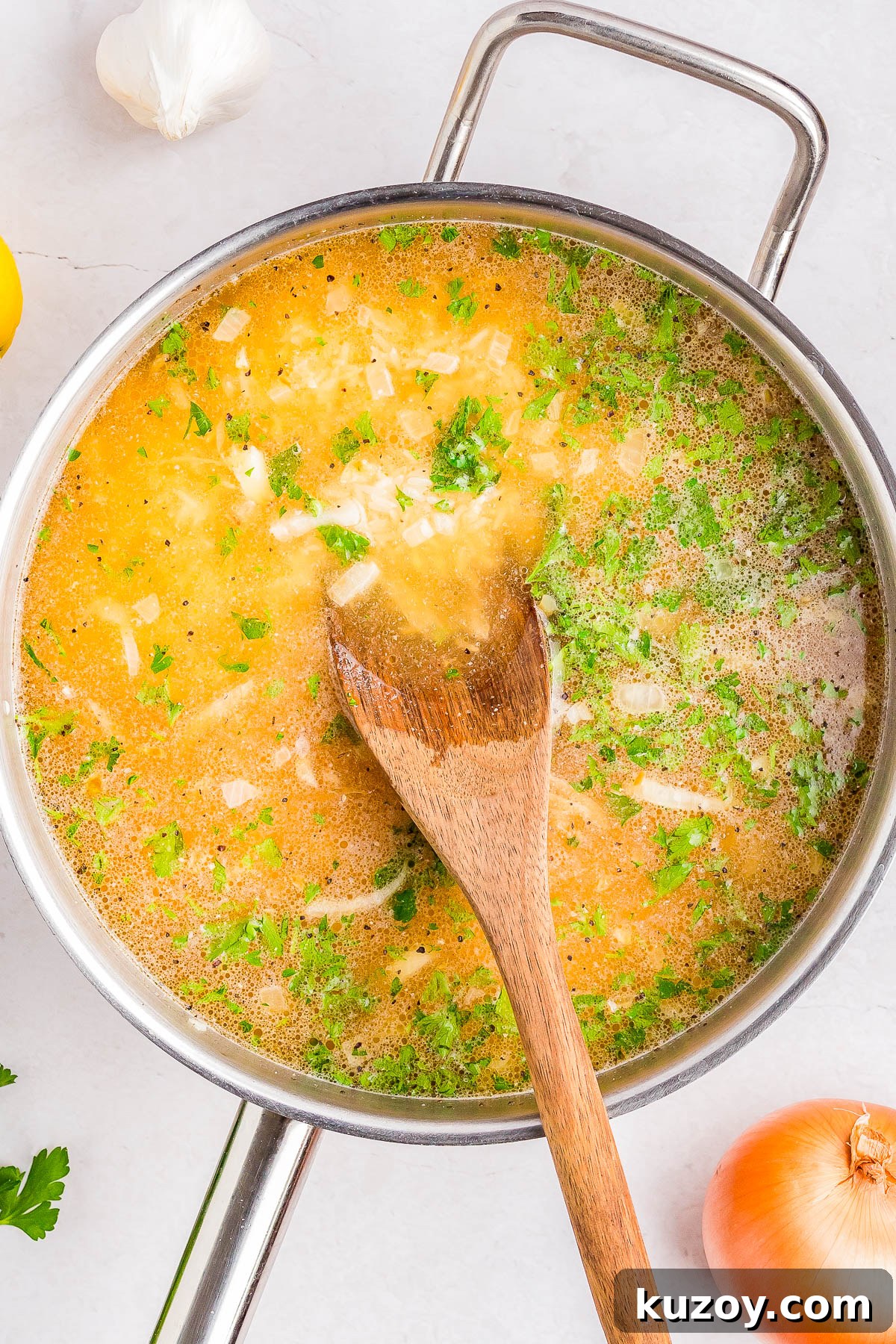 A pot of soup with visible herbs and onion pieces.