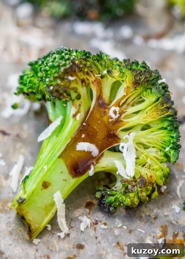 Roasted broccoli floret with melted cheese on a baking sheet.