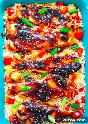 Baked teriyaki chicken over rice garnished with sesame seeds and green onions.