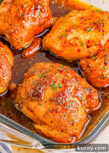 Close-up of four glazed and seasoned chicken thighs in a glass baking dish.