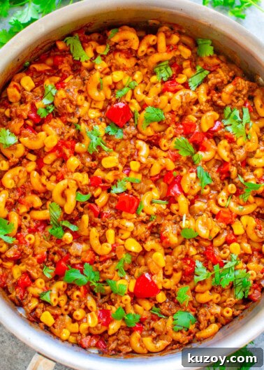 Pot of homemade goulash with macaroni, tomatoes, and ground meat, garnished with fresh parsley.