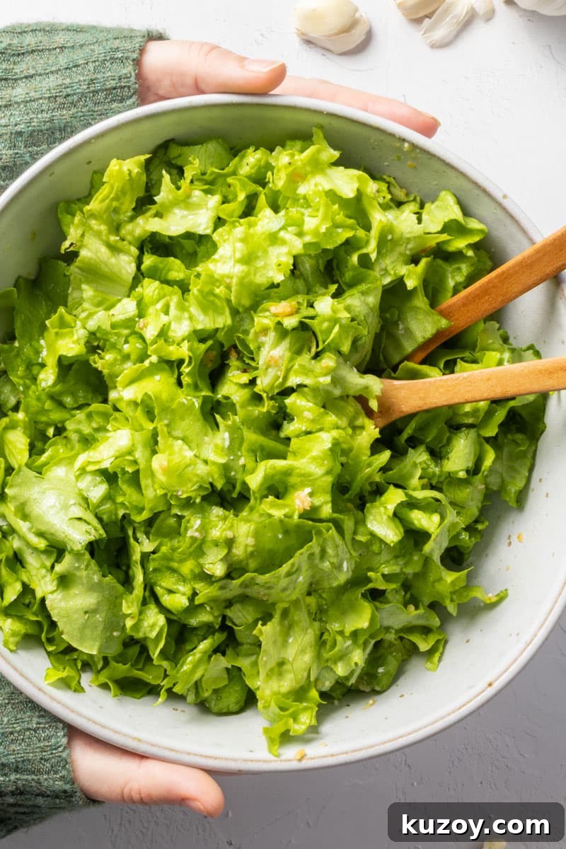Toasted Garlic Salad with Crispy Garlic Dressing 2 Two hands in a green jumper holding a bowl of green salad.