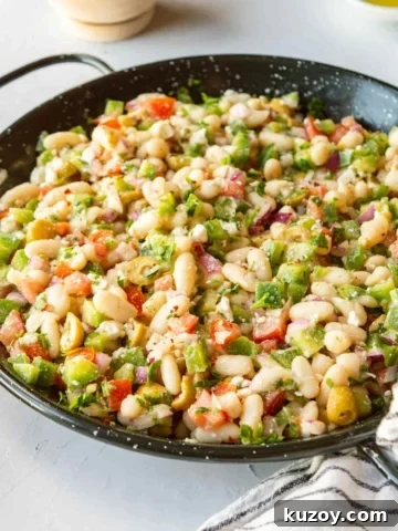 A black pan with white bean salad on a white background.