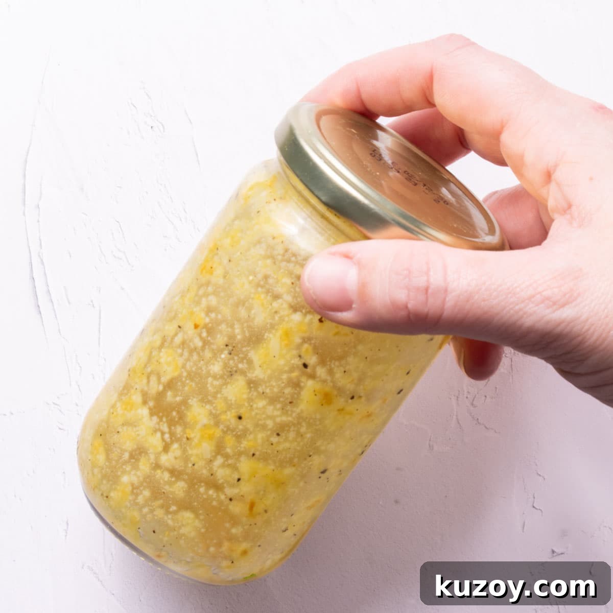 Toasted Garlic Salad with Crispy Garlic Dressing 7 A glass jar with a gold screwtop with a pale yellow dressing in it.