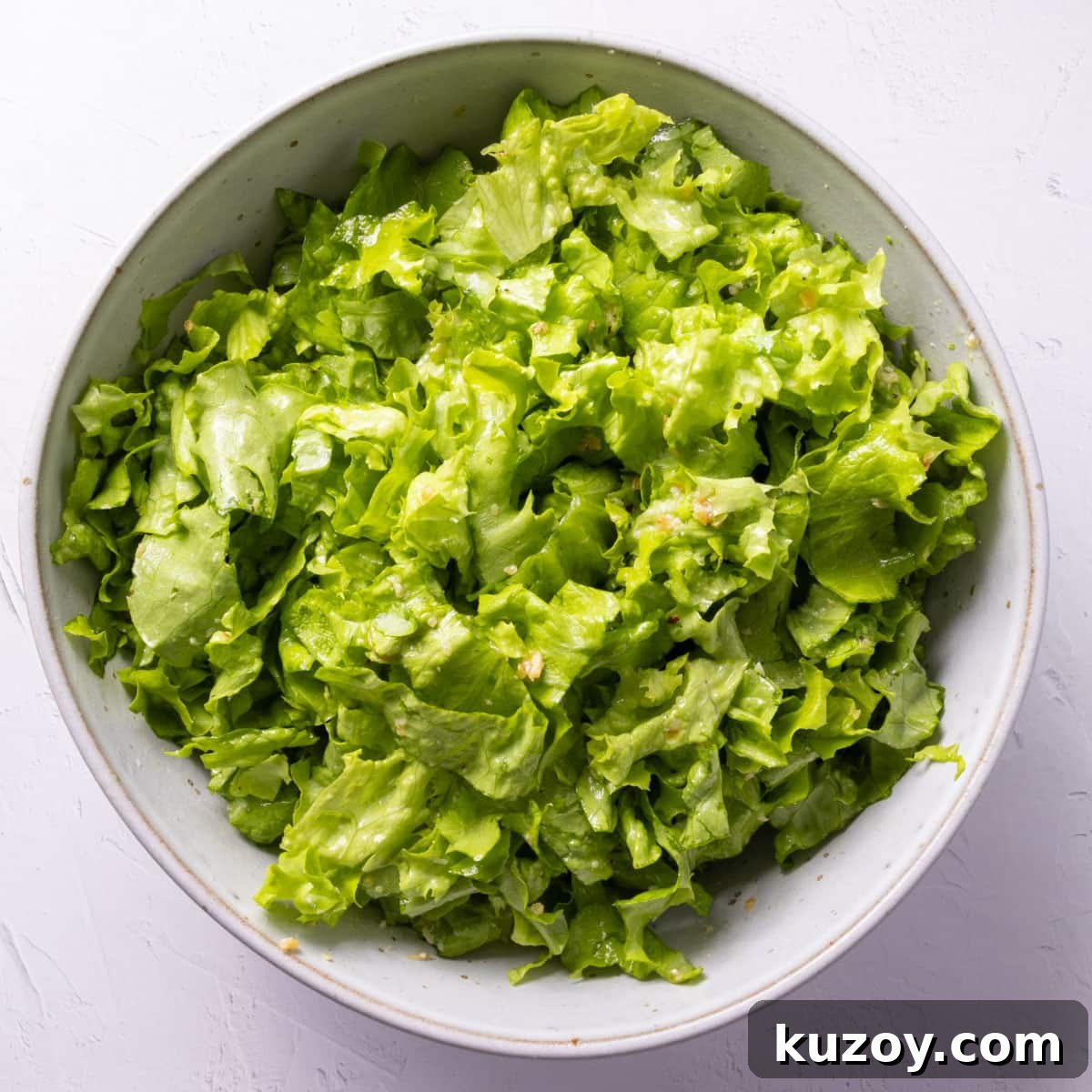 Toasted Garlic Salad with Crispy Garlic Dressing 9 A bowl of green chopped dressed salad on a white backdrop.
