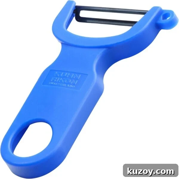 A blue vegetable peeler with a horizontal stainless steel blade and a wide handle featuring a large hole at the end for hanging.