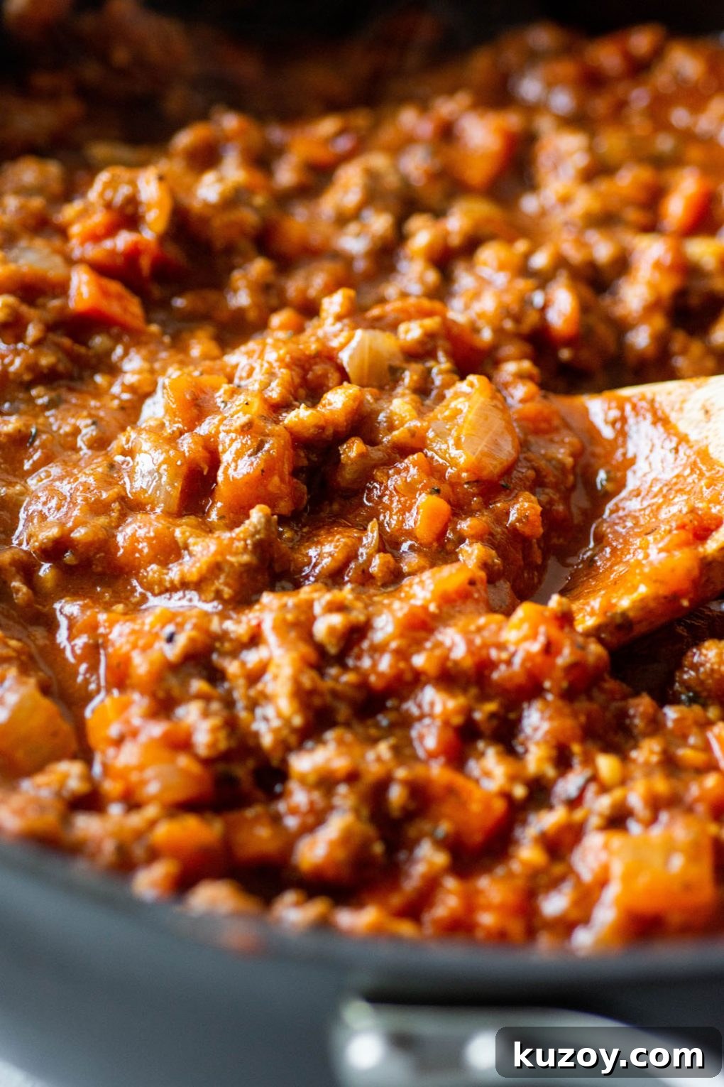 Pumpkin Ragu Pasta Sauce with Canned Pumpkin 4 Up close shot of a wooden spoon dipping into pumpkin ragu pasta sauce.