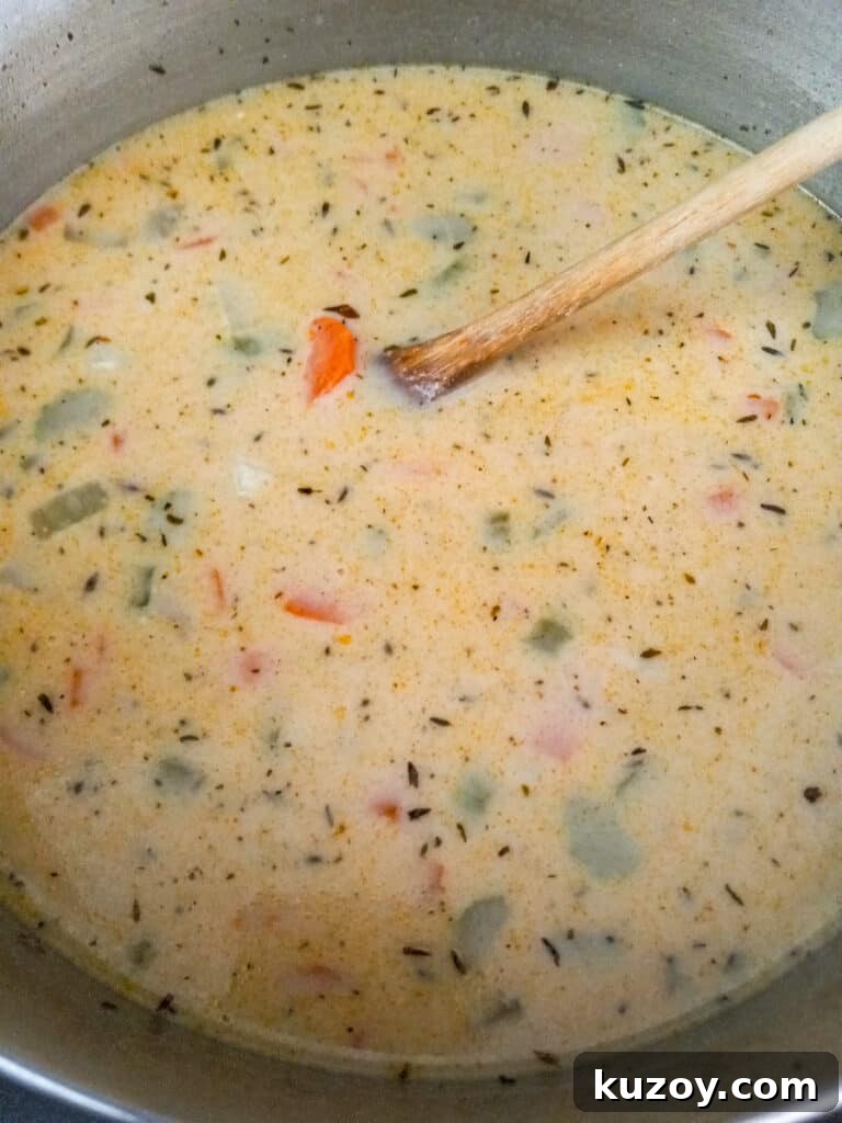 making soup in a large pot, milk and broth added to the veggies in the pot.