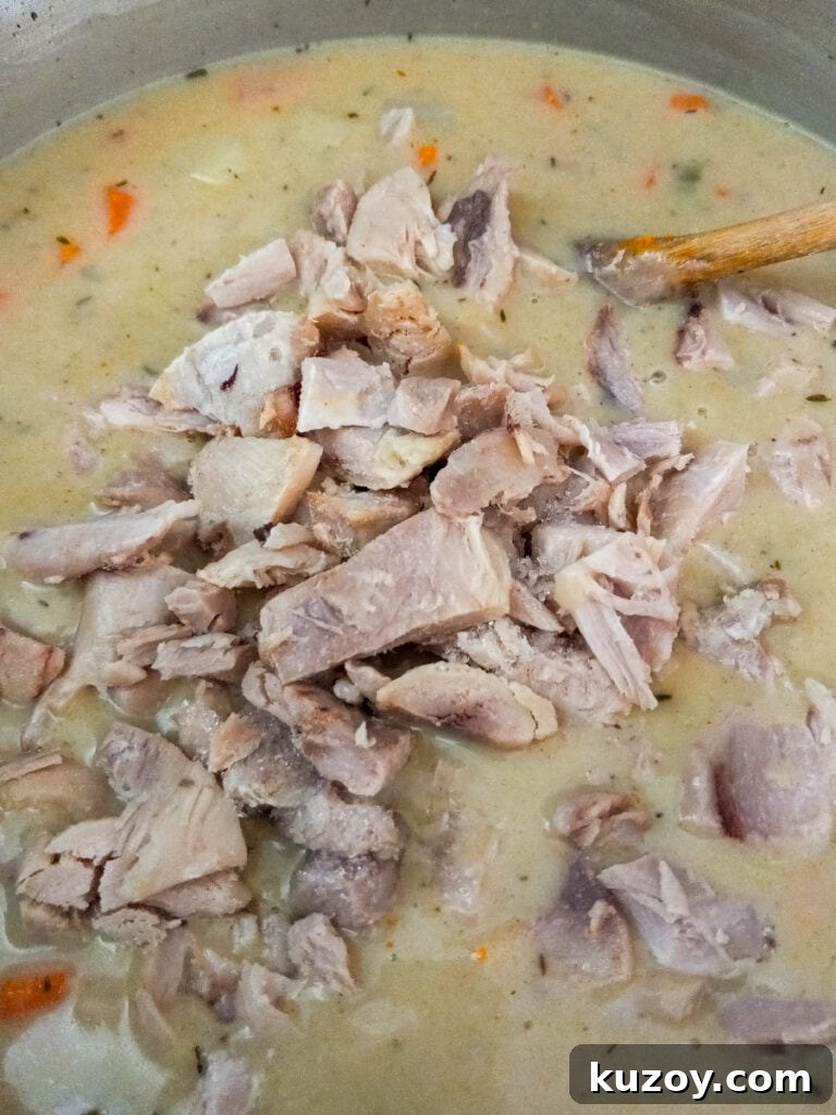 adding cooked and chopped chicken to the pot.