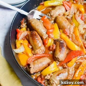 A fork is in the pan with the one pot sausage and peppers and a yellow napkin on the corner of the pan.