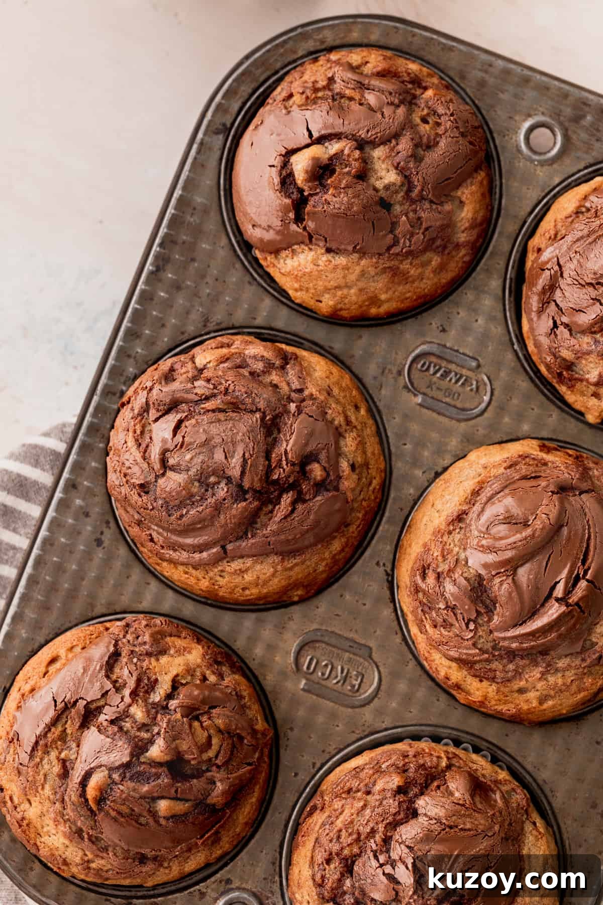Nutella Banana Muffins Recipe — Gooey Chocolate Banana Muffins 2 Nutella banana muffins in a muffin pan.