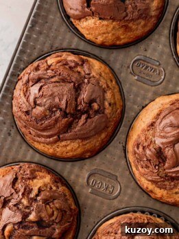 Nutella Banana Muffins Recipe — Gooey Chocolate Banana Muffins 12 Nutella banana muffins in a muffin pan.