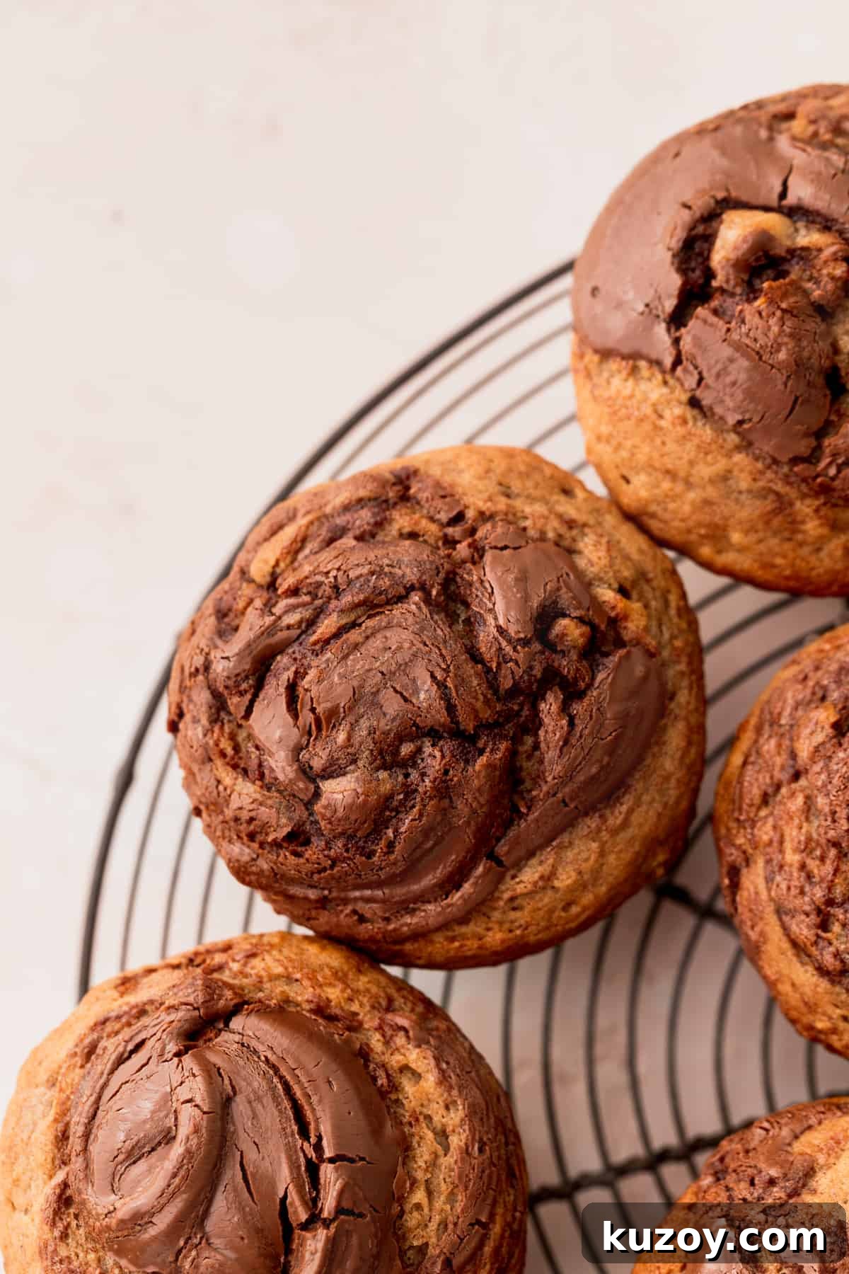 Nutella Banana Muffins Recipe — Gooey Chocolate Banana Muffins 3 Nutella banana muffins on a wire rack.