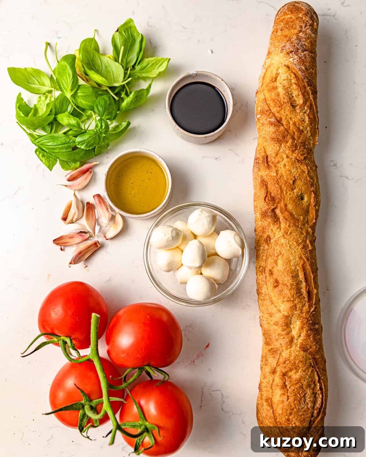 ingredients to make bruschetta with mozzarella - tomatoes, mozzarella, garlic, balsamic vinegar, fresh basil, olive oil, and bread. 