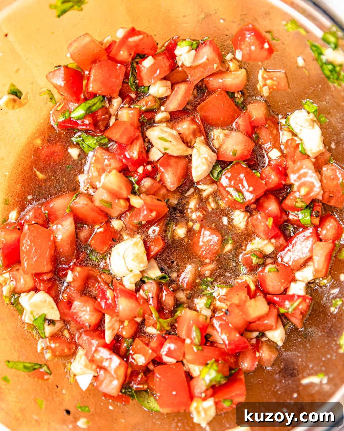 diced tomatoes, basil, garlic, and mozzarella mixed together in a bowl with olive oil and balsamic vinegar.