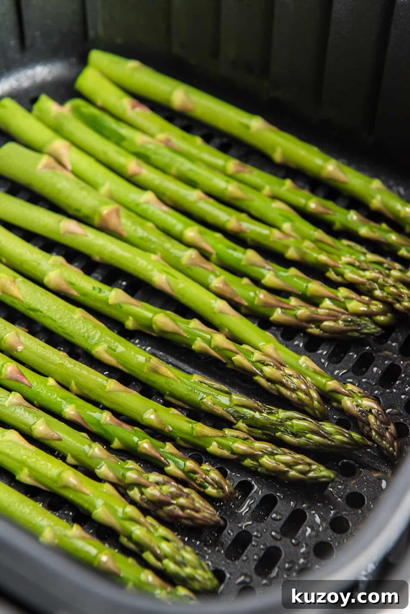 Crispy Air Fryer Asparagus Recipe with Garlic and Lemon 2 Air fryer basket with oiled asparagus in it.