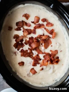 Creamy Slow Cooker Potato and Bacon Soup Recipe 6 creamy potato soup with bacon on top in a slow cooker.