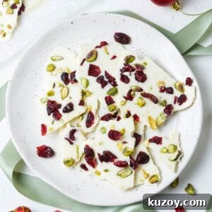 Round plate with bark, surrounded by some cranberries and decorations.