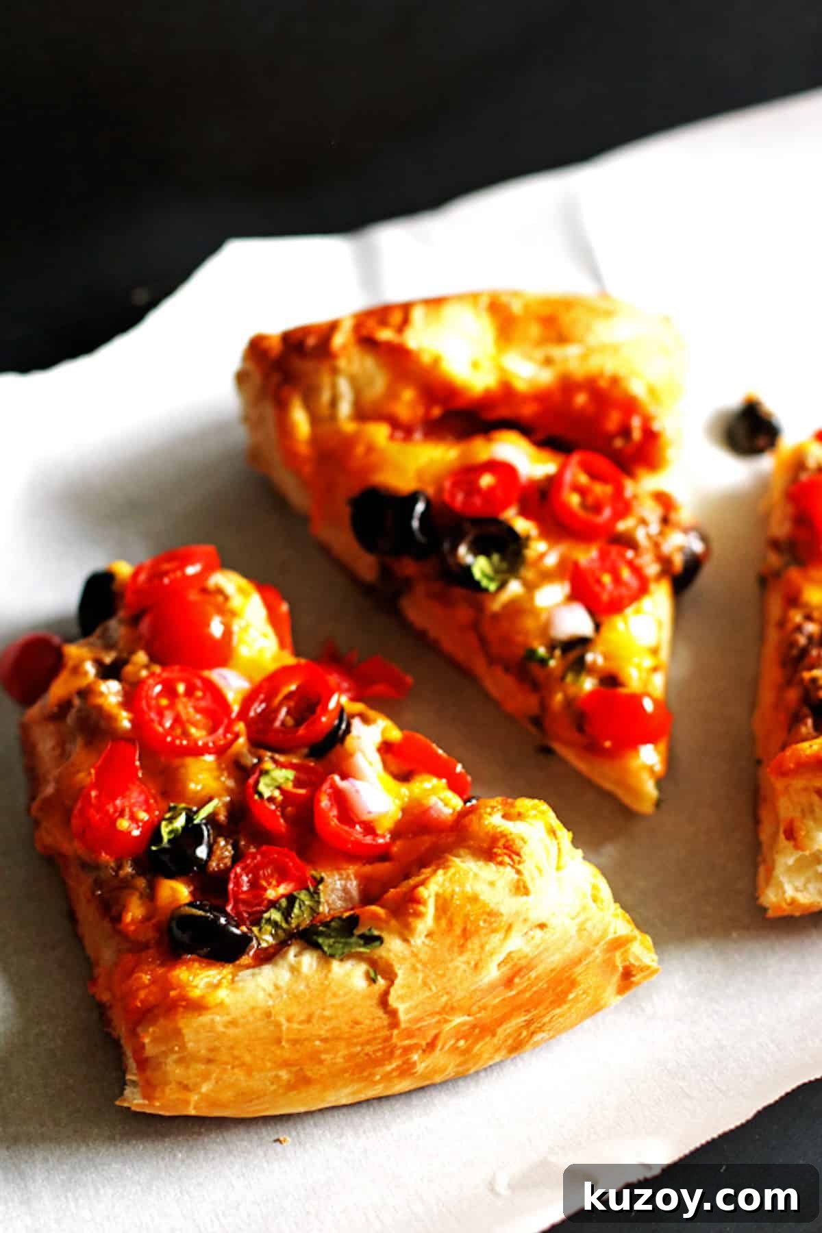 Taco Pizza Recipe: How to Make Homemade Taco Pizza from Scratch 2 Three slices of taco pizza topped with tomatoes, cilantro, and black olives.