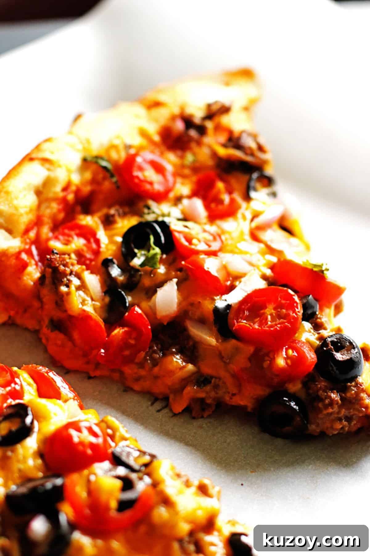 Taco Pizza Recipe: How to Make Homemade Taco Pizza from Scratch 5 A slice of taco pizza topped with fresh tomatoes, cilantro, cheese, olives, and taco meat.