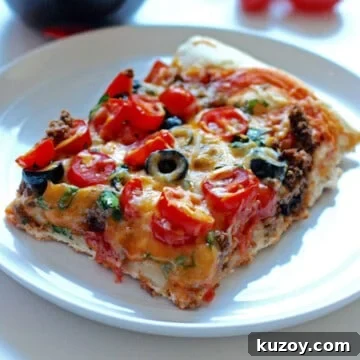 Taco Pizza Recipe: How to Make Homemade Taco Pizza from Scratch 7 A square slice of taco pizza topped with cheese, black olives, and tomatoes.