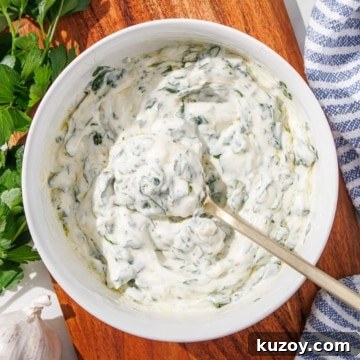 A bowl of chimichurri aioli with a gold spoon in it.