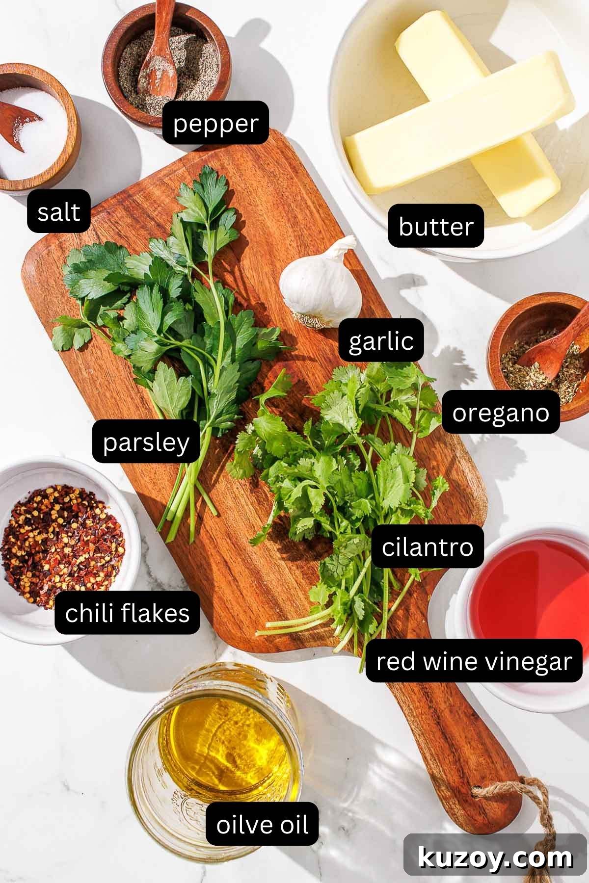 A cutting board with the labeled ingredients for chimichurri butter on it.