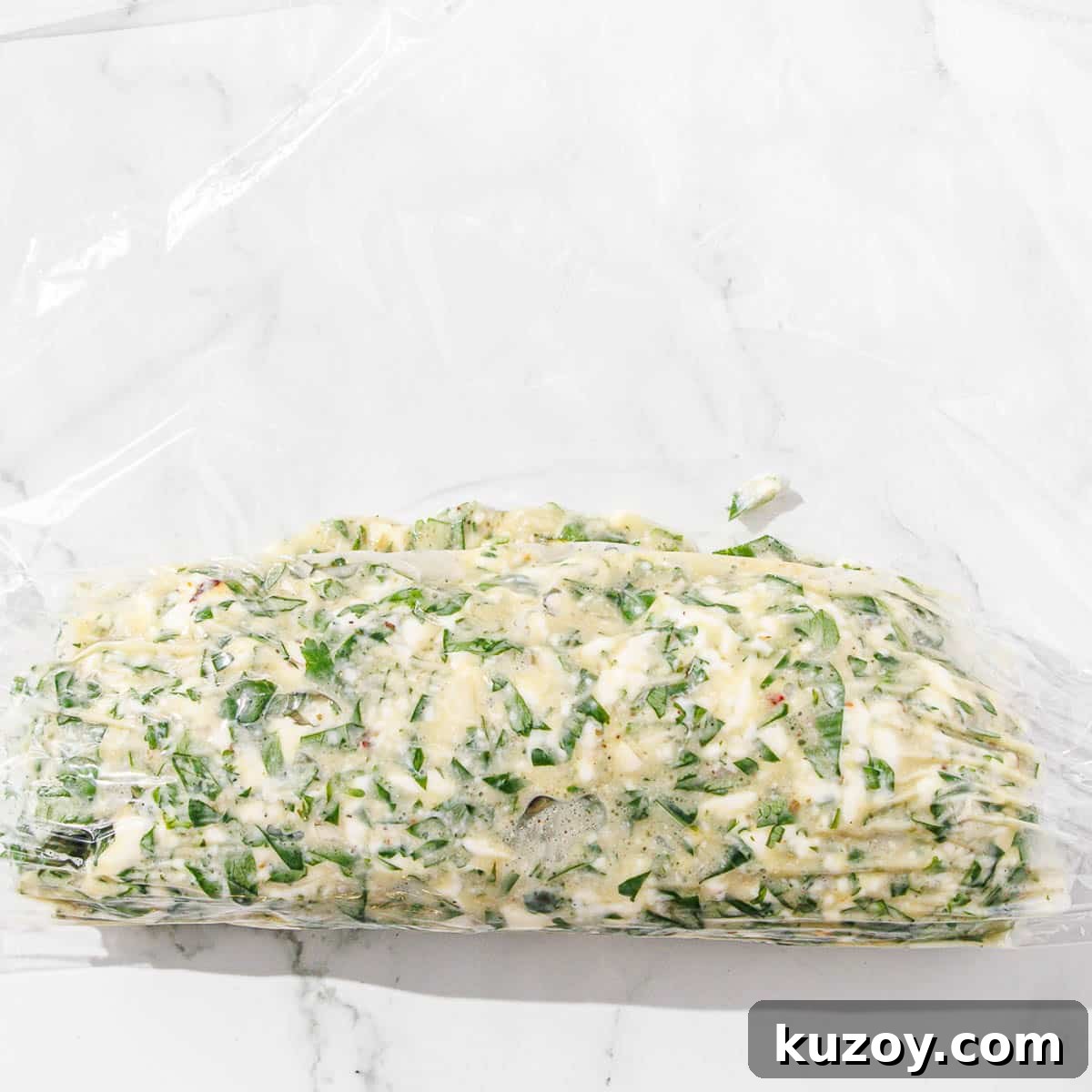 Chimichurri butter is rolled in a piece of plastic wrap.
