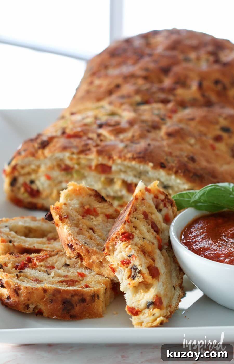 How to Make Homemade Pizza Bread (Crispy, Cheesy Recipe) 2 loaf of sliced homemade pizza bread with a bowl of pizza sauce.