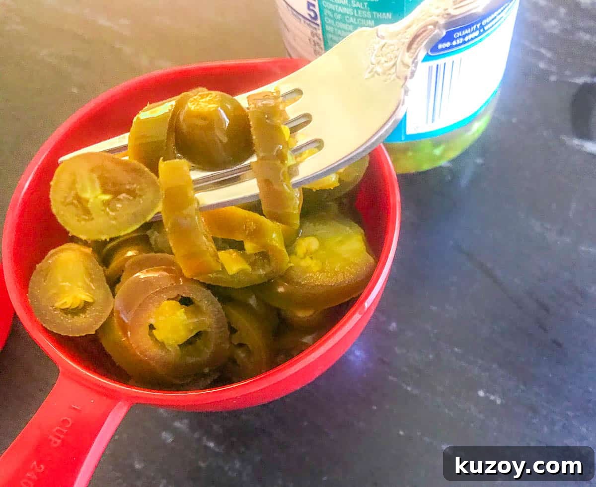 Jalapenos in a measuring cup with a fork