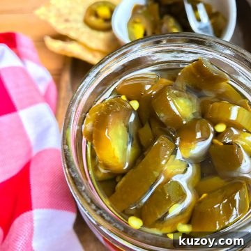Candied jalapenos in a jar next to a red and white checkered napkin