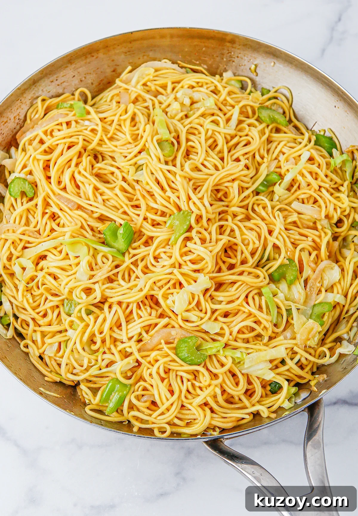 Panda Express Chow Mein Recipe: Copycat Version for Home Cooking 6 A sautee pan filled with cooked chow mein noodles garnished with sliced green onion.