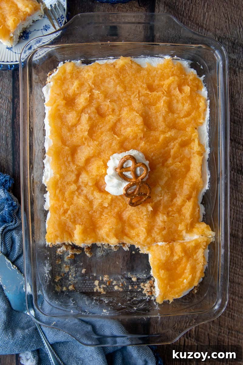 Creamy Pineapple Pretzel Salad Recipe with Crunchy Crust 5 overhead shot of pineapple pretzel salad in a glass dish with a blue towel next to it