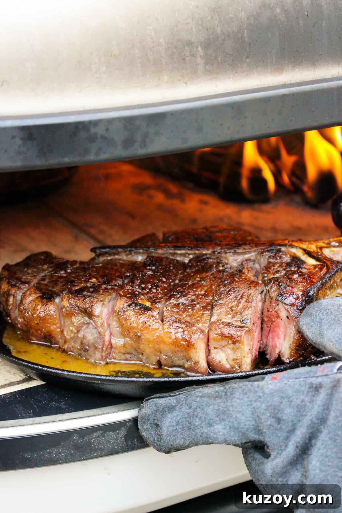 sliced peter luger style steak being placed back into the pizza oven