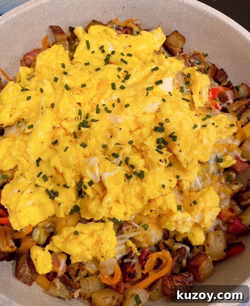 Country Skillet Breakfast Scramble with Sausage & Potatoes 5 Adding scrambled eggs to cooked skillet veggies and meats. Topped with more chopped chives.