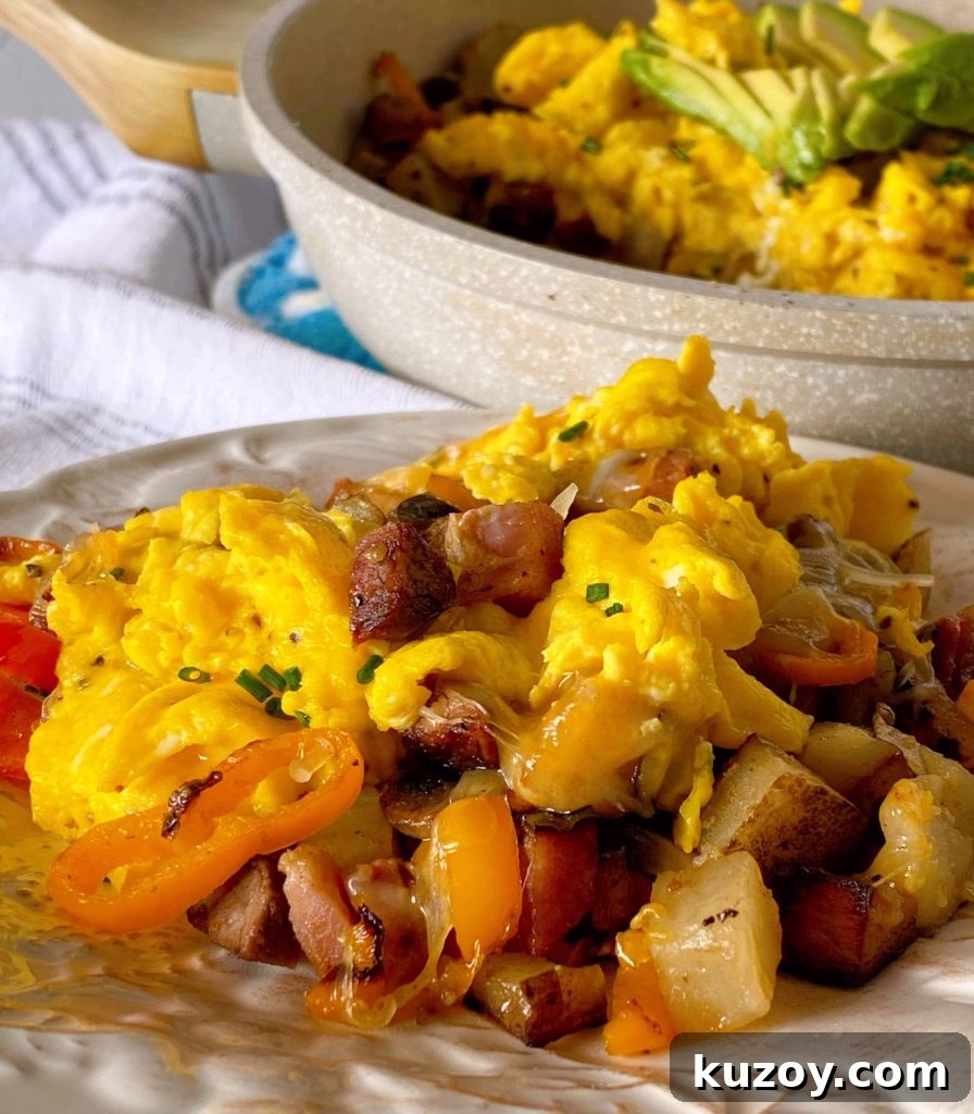 Country Skillet Breakfast Scramble with Sausage & Potatoes 7 Skillet Breakfast on a serving plate with a skillet full in the background.