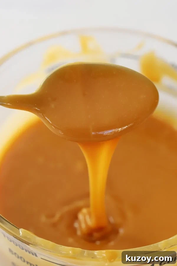 How to Make Classic Homemade Caramel Candy at Home 5 A spoon covered with this easy caramel recipe, drizzling it back into the bowl.