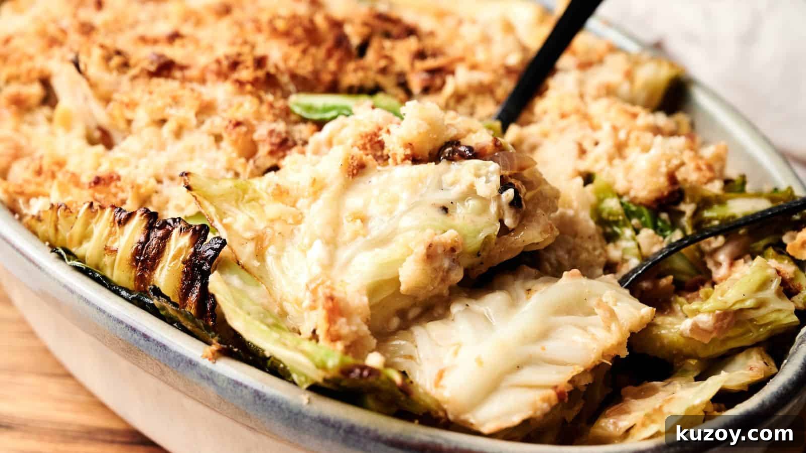 33 Must-Bring Thanksgiving Potluck Recipes for Every Year 13 A close-up of a baked casserole dish filled with creamy cabbage gratin, topped with a golden breadcrumb crust, with a serving spoon partially visible.